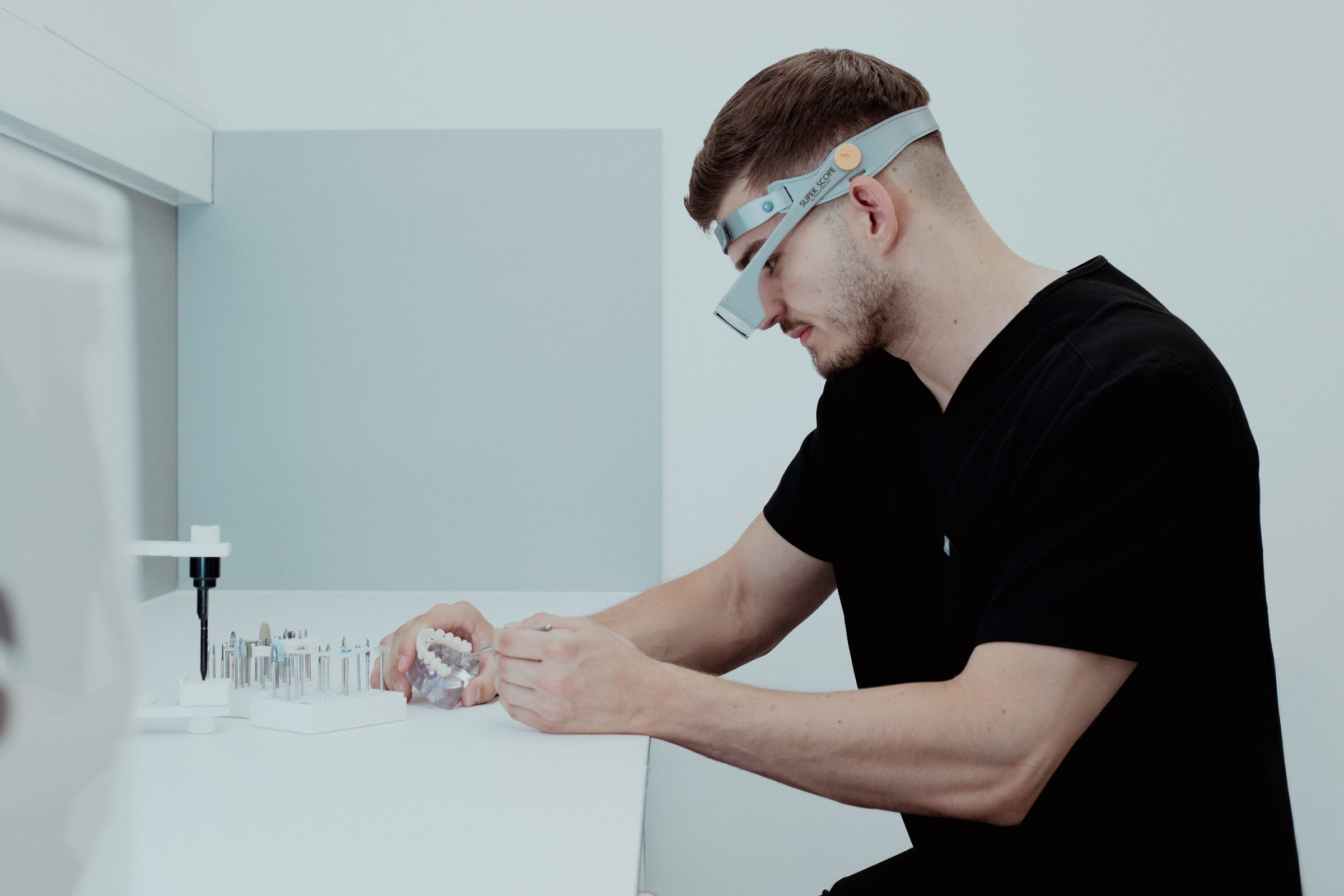 Zahntechniker mit Lupenbrille im praxiseigenen digitalen Dental-Labor